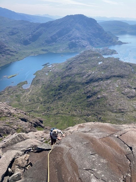 A man climbing a rock face on a sunny day