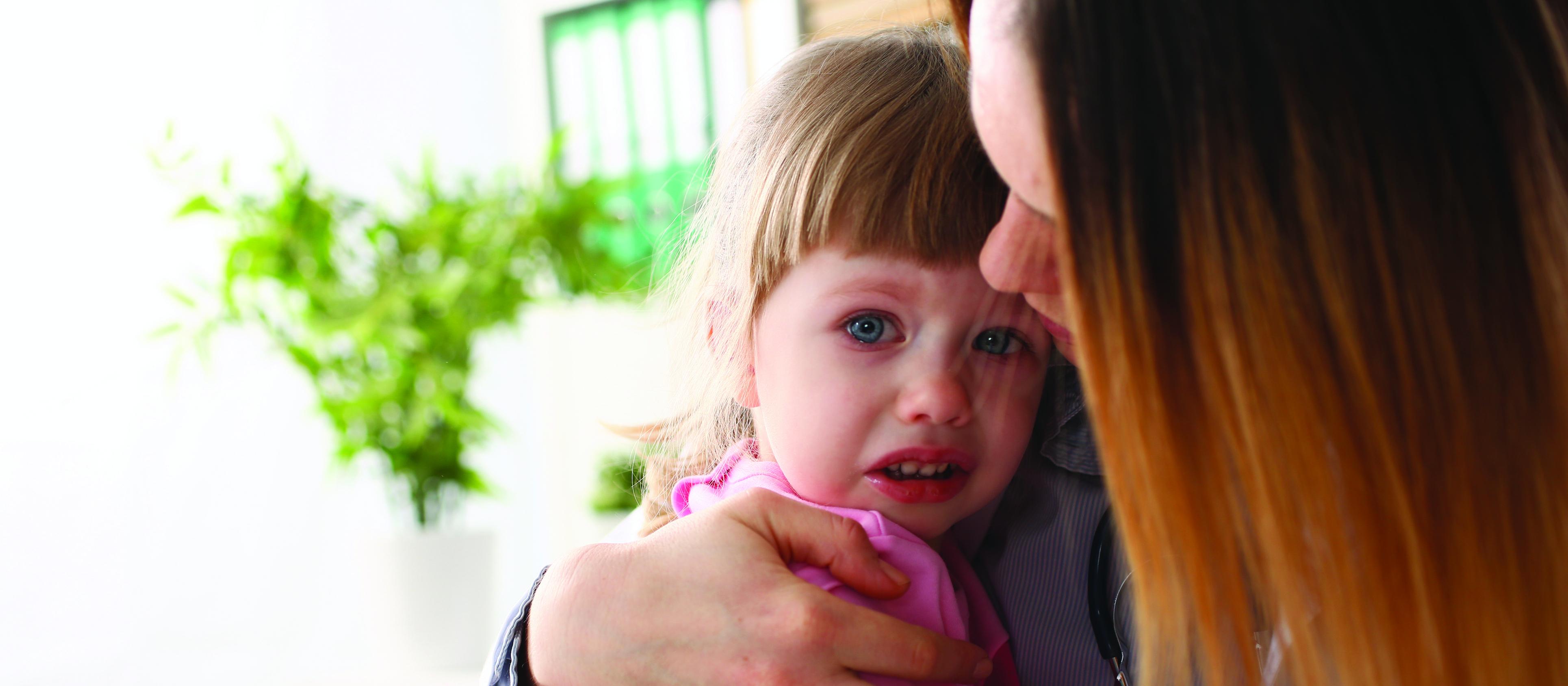 Woman holding a child, young child, sad,