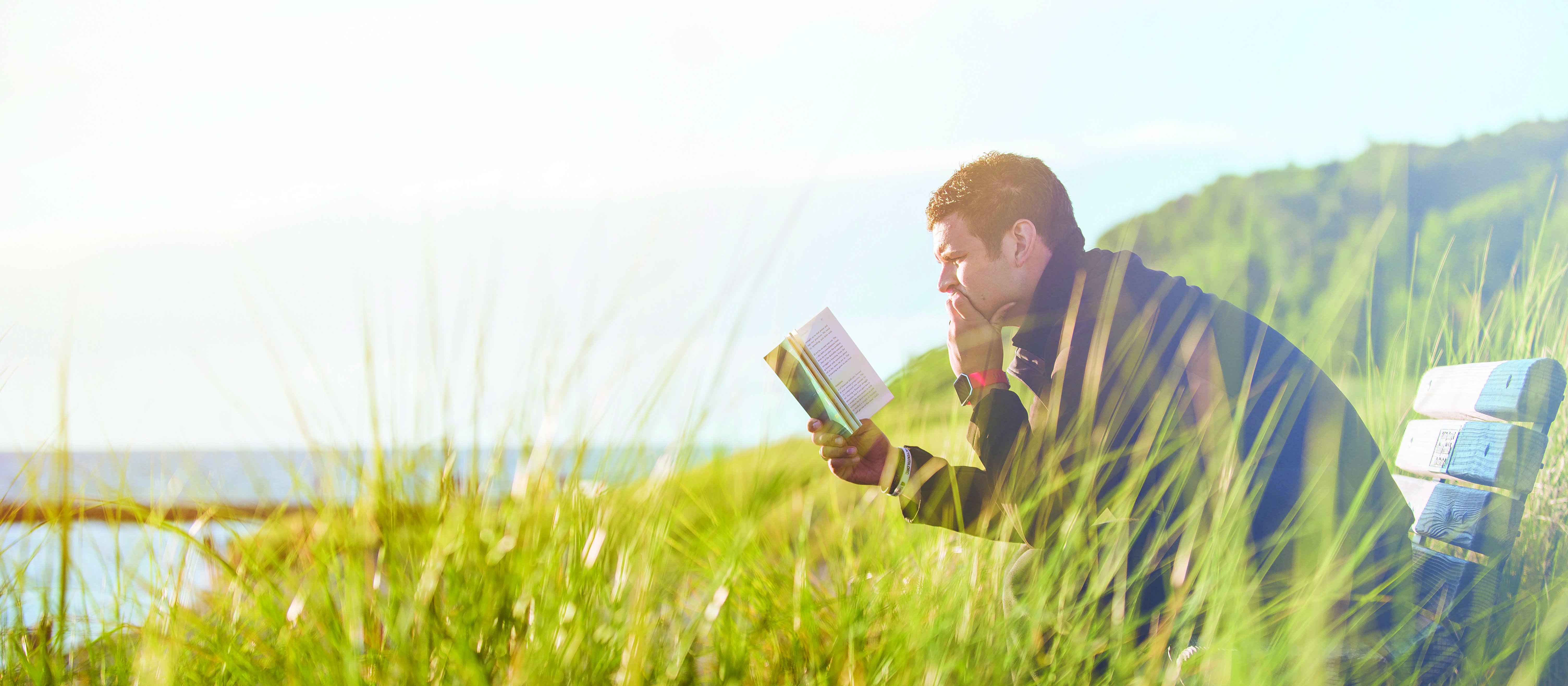 Man reading a book in a field_Ben White on Unsplash