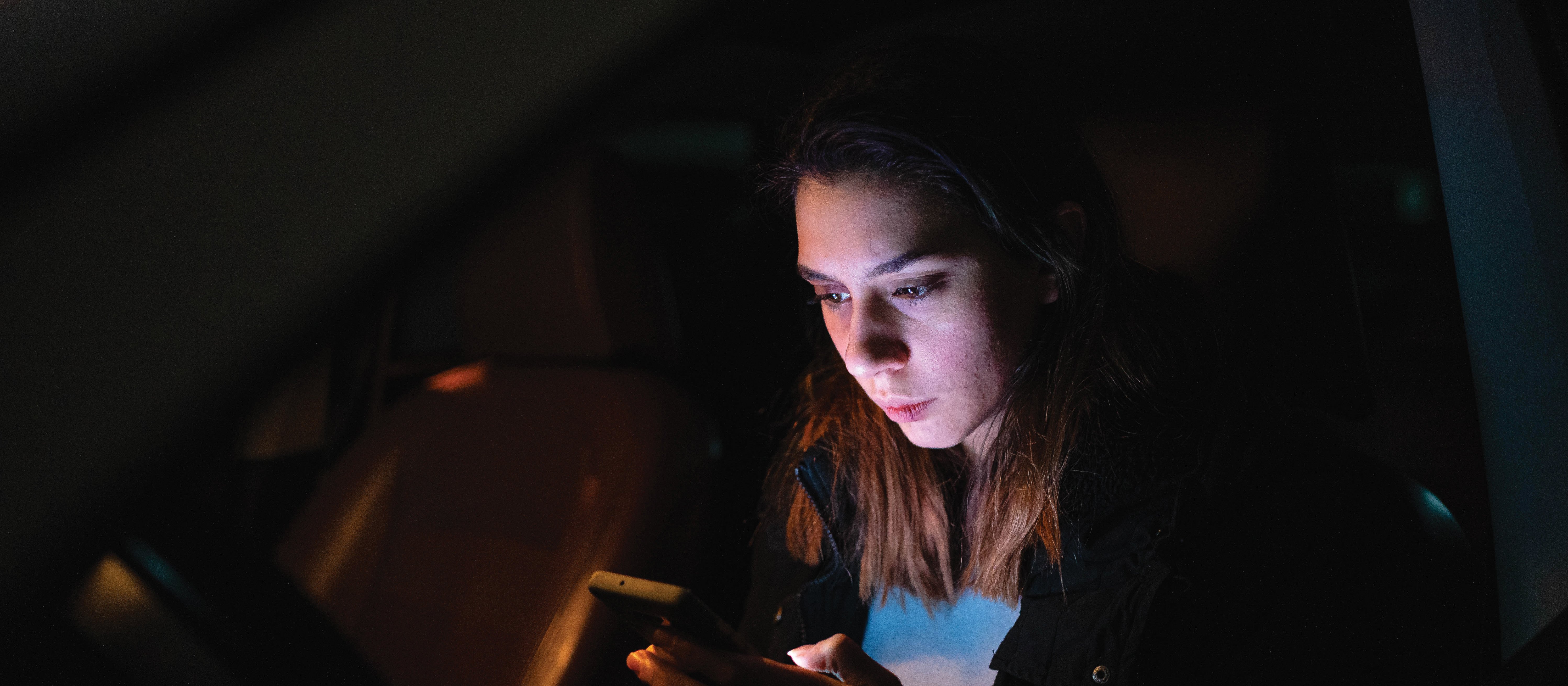 Woman on phone in the dark CR Perinjo on iStock