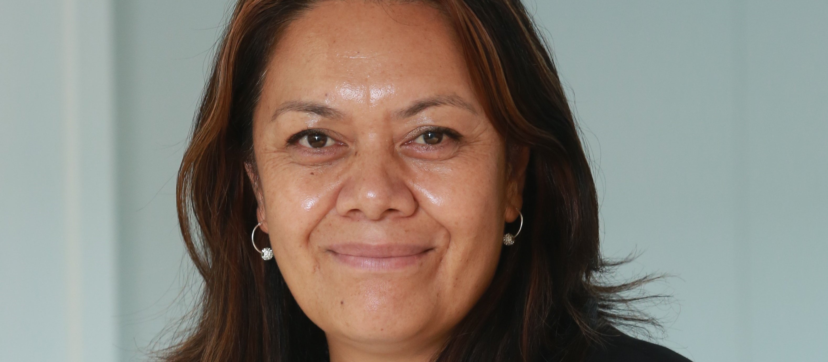 Margie Apa, wearing a white top with a flower and black blazer, smiling at camera