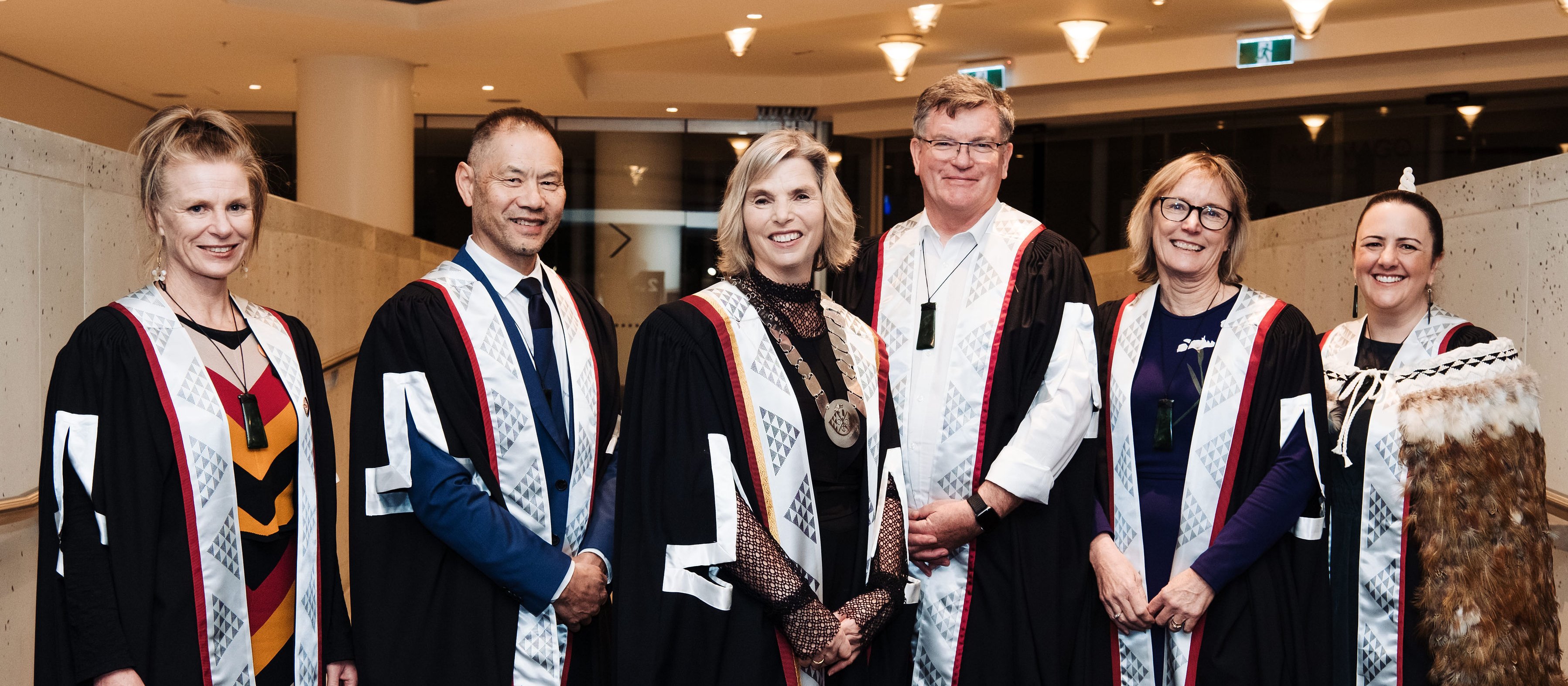 Photo shows RNZCGP distinguished fellows standing in a line, wearing gowns, and smiling at camera