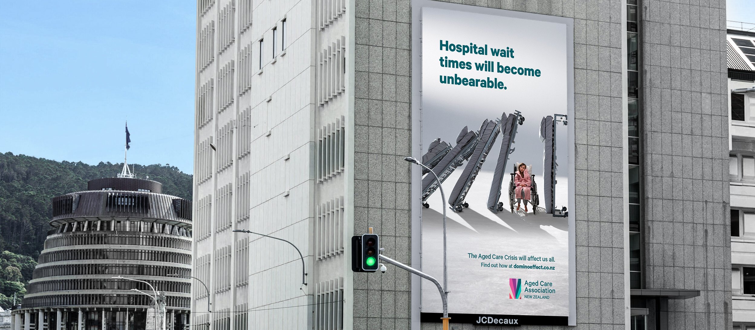 Billboard for Aged Care Association campaign on side of building with traffic in front and Parliament buildings behind