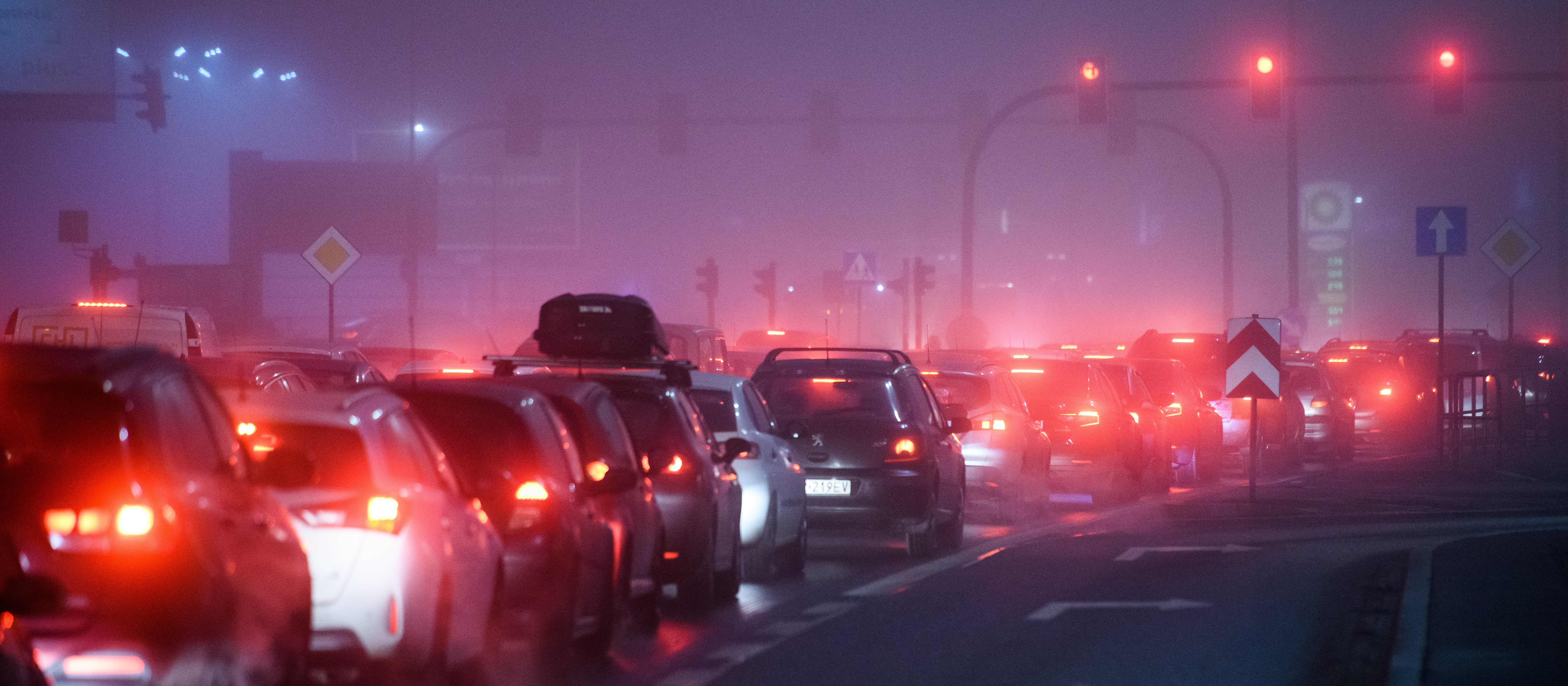 A line of cars in a traffic jam with smog haze