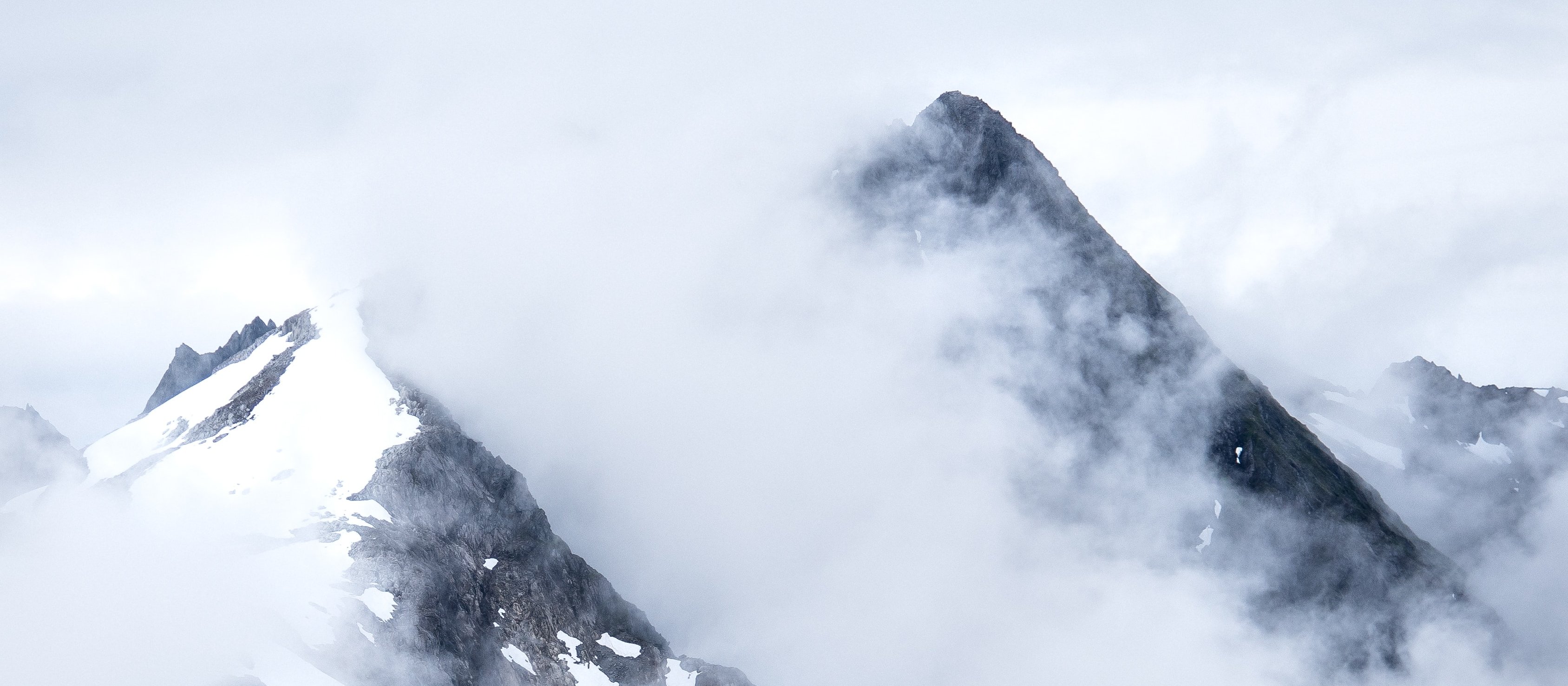 Snow-capped mountain tops peaking through clouds