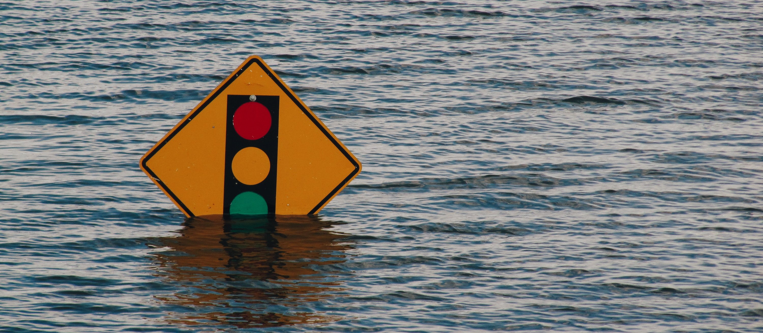 Submerged traffic sign, flooding [Kelly Sikkema on Unsplash]