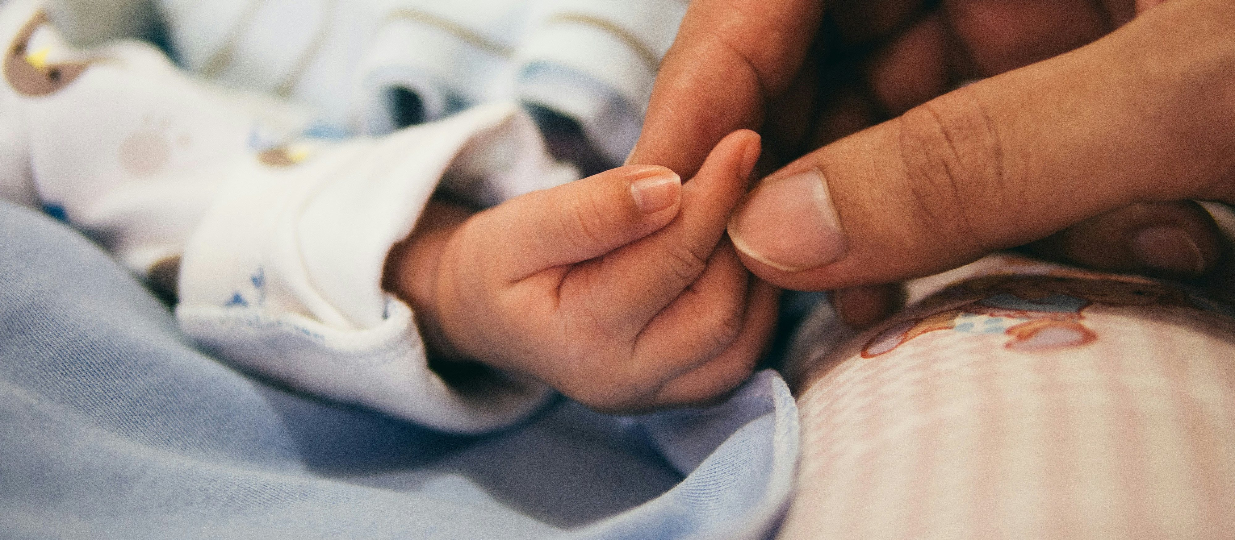 Baby and adult hand CR Aditya Romansa on Unsplash