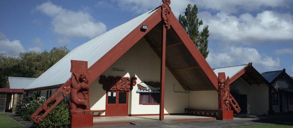 Front of Papakura Marae, viewed slightly from the side. Blue sky, with some white clouds in background