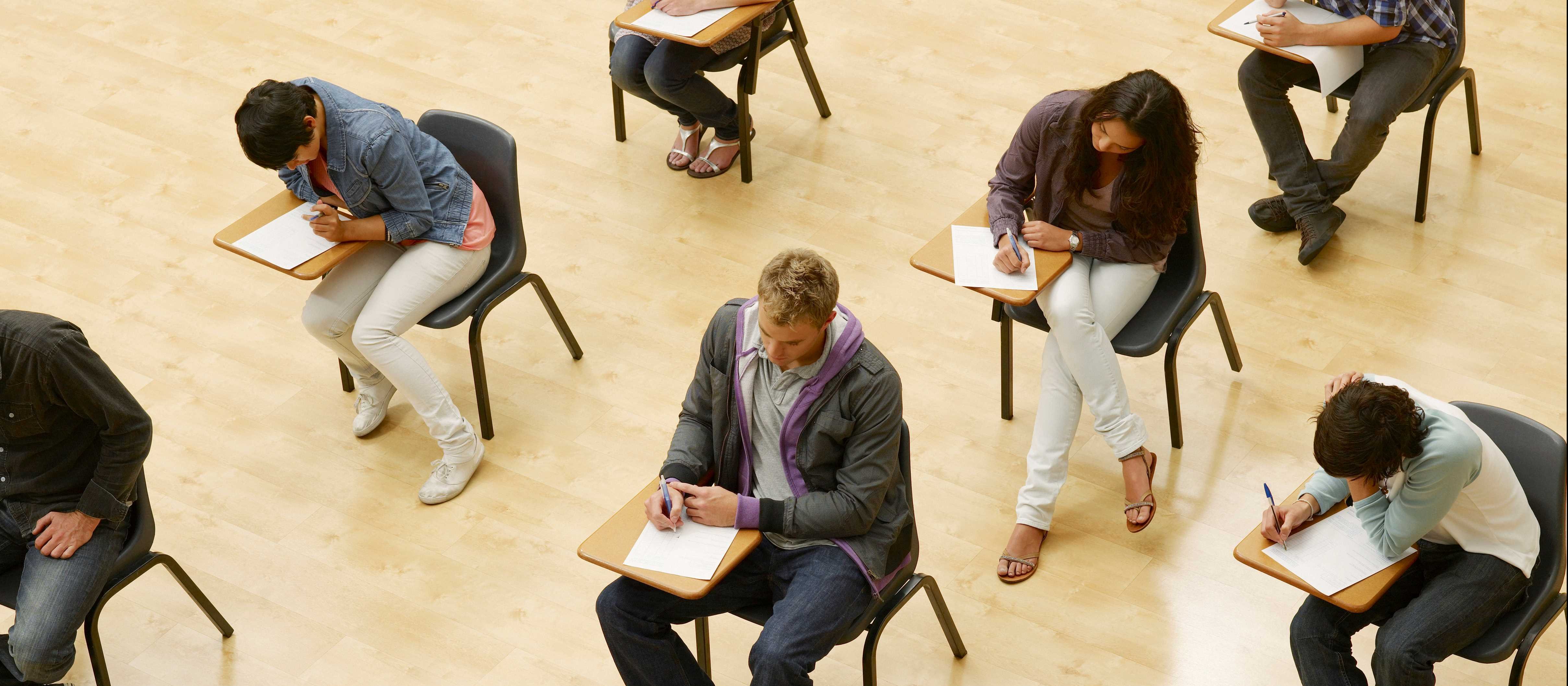 Students sitting in rows of desks, doing an exam