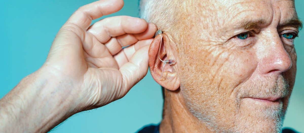 Man adjusting hearing aid