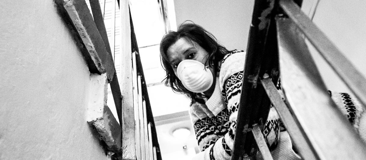 Woman wearing a mask on a balcony_Cold Snowstorm on iStock