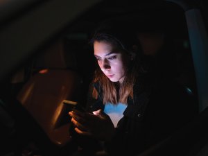 Woman on phone in the dark CR Perinjo on iStock