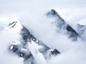 Snow-capped mountain tops peaking through clouds