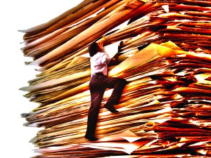 Man climbing paper stack [Image: Luis Portugal on iStock]