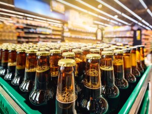 Crate of beer in foreground, with supermarket shelves in background