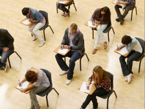 Students sitting in rows of desks, doing an exam
