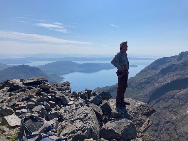 Man standing on mountain overlooking expansive lake on a sunny day