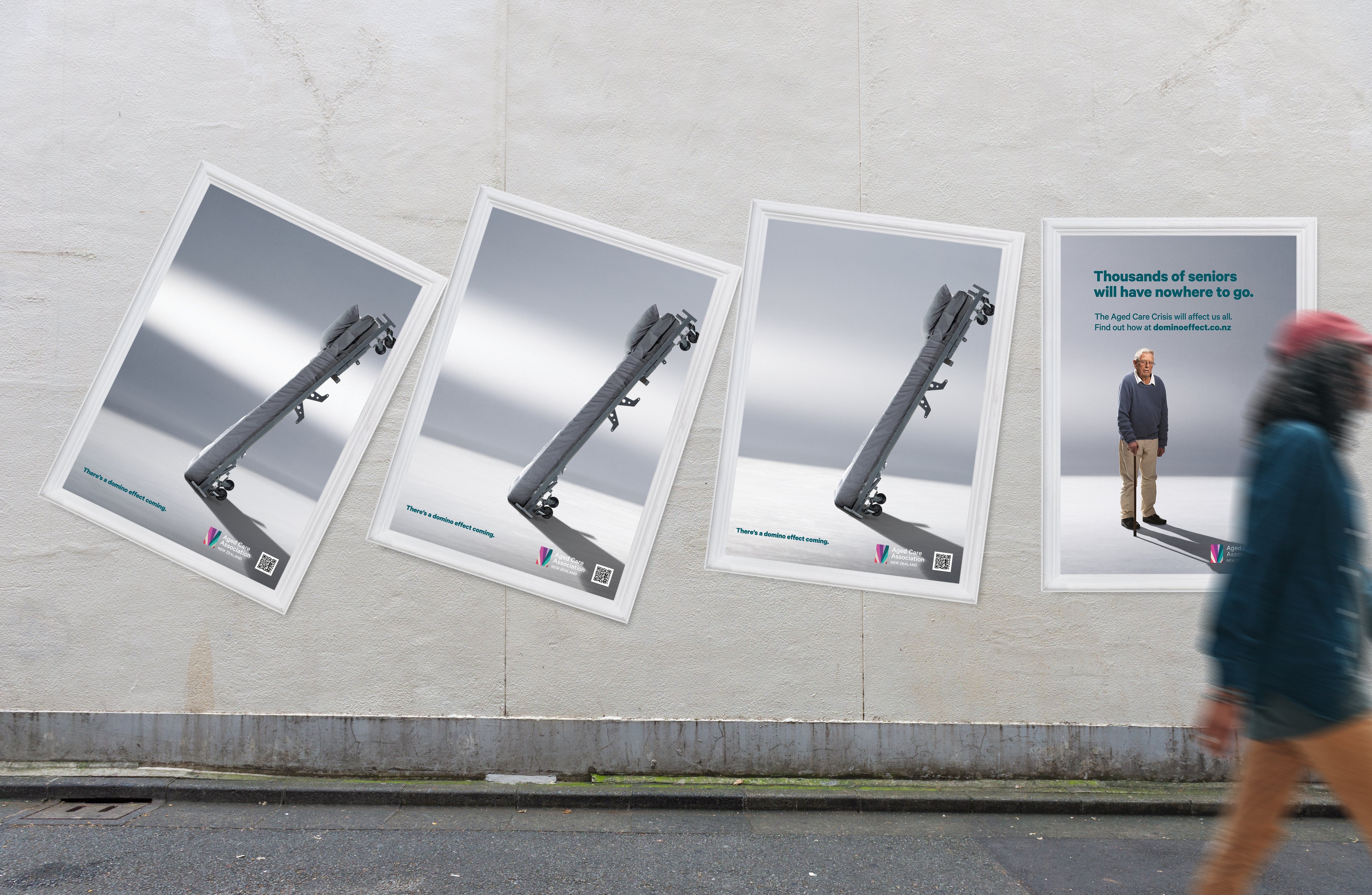 Domino Effect street posters on a wall, with a person walking past on the right
