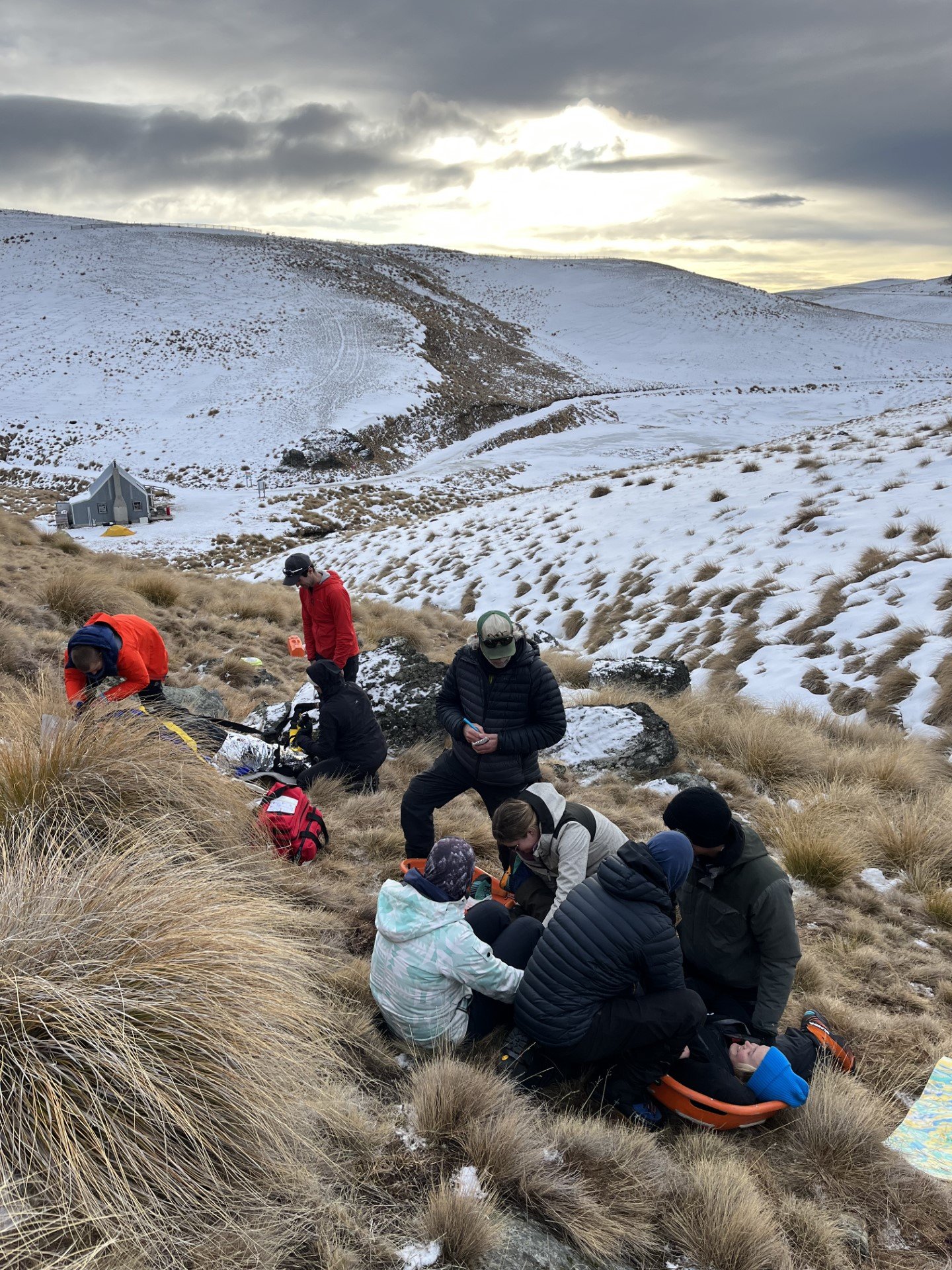 Medical students simulating a rescue of an injured person close to a ski hut on Cardrona, one person in a stretcher 